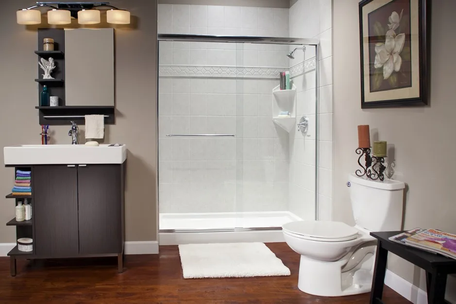 Bathroom with a white shower, tile-look wall panels, a sliding glass door and a corner shelf, next to a dark wood vanity