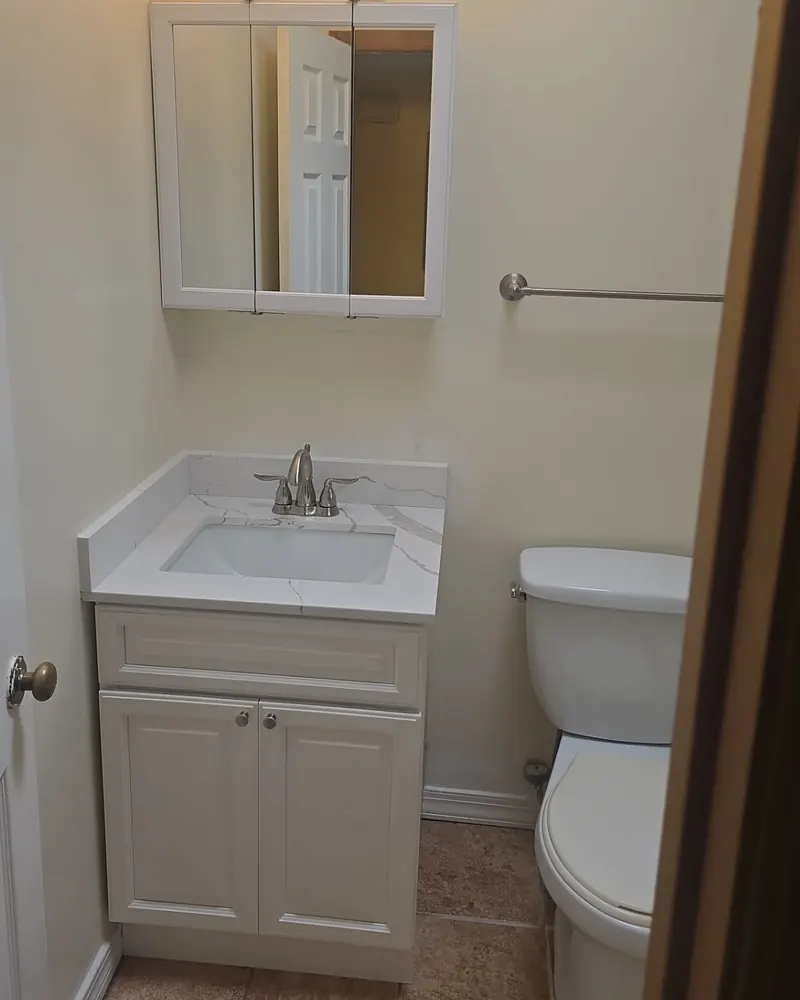 After: new white vanity with a marble-look top, brushed nickel faucet and matching mirror cabinet